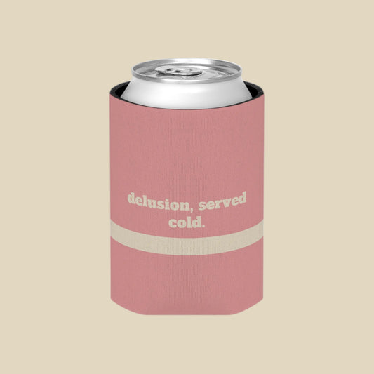 A pink can cooler sleeve with a silver aluminum can inside, featuring the text 'delusion, served cold.' in beige on the front, set against a plain white background.