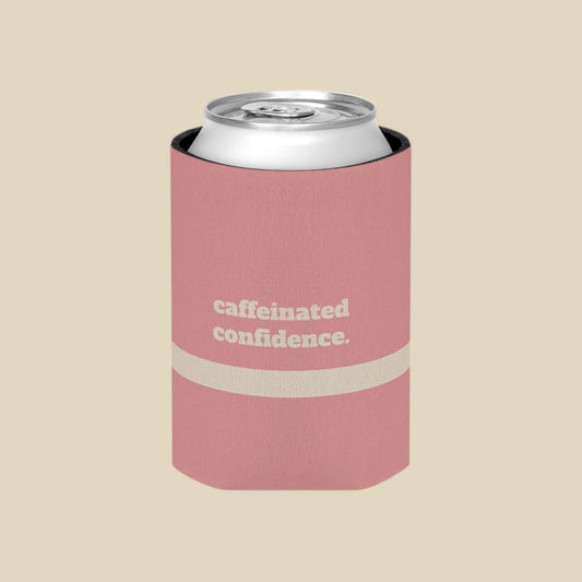 A pink can cooler sleeve holding a silver aluminum can, featuring the text 'caffeinated confidence.' in white on the front, set against a plain white background.